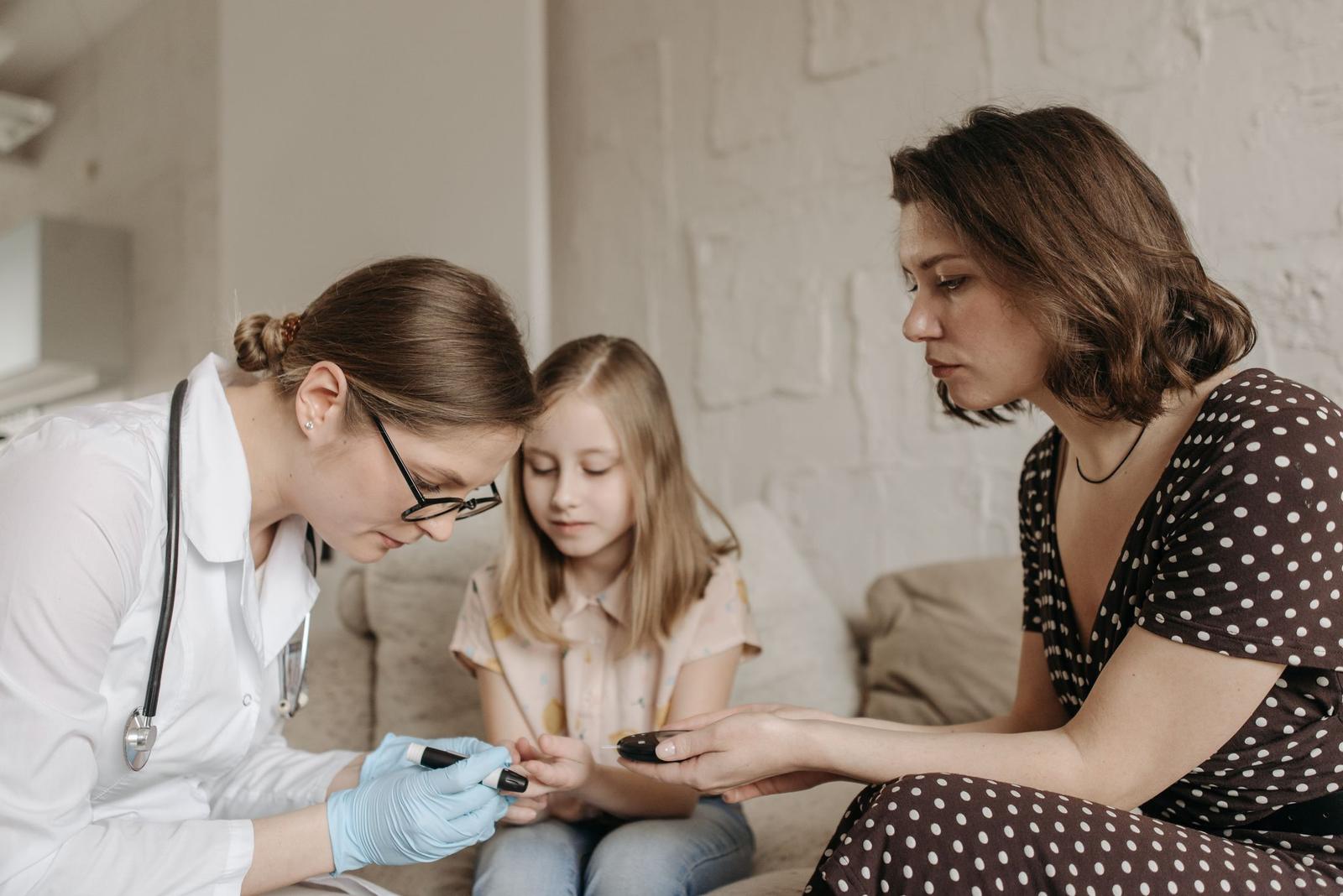 A doctor checks a young girl while her mother watches