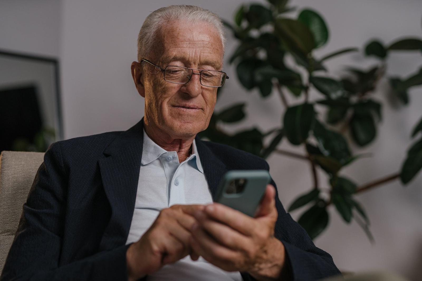 An older man reads a message on his phone